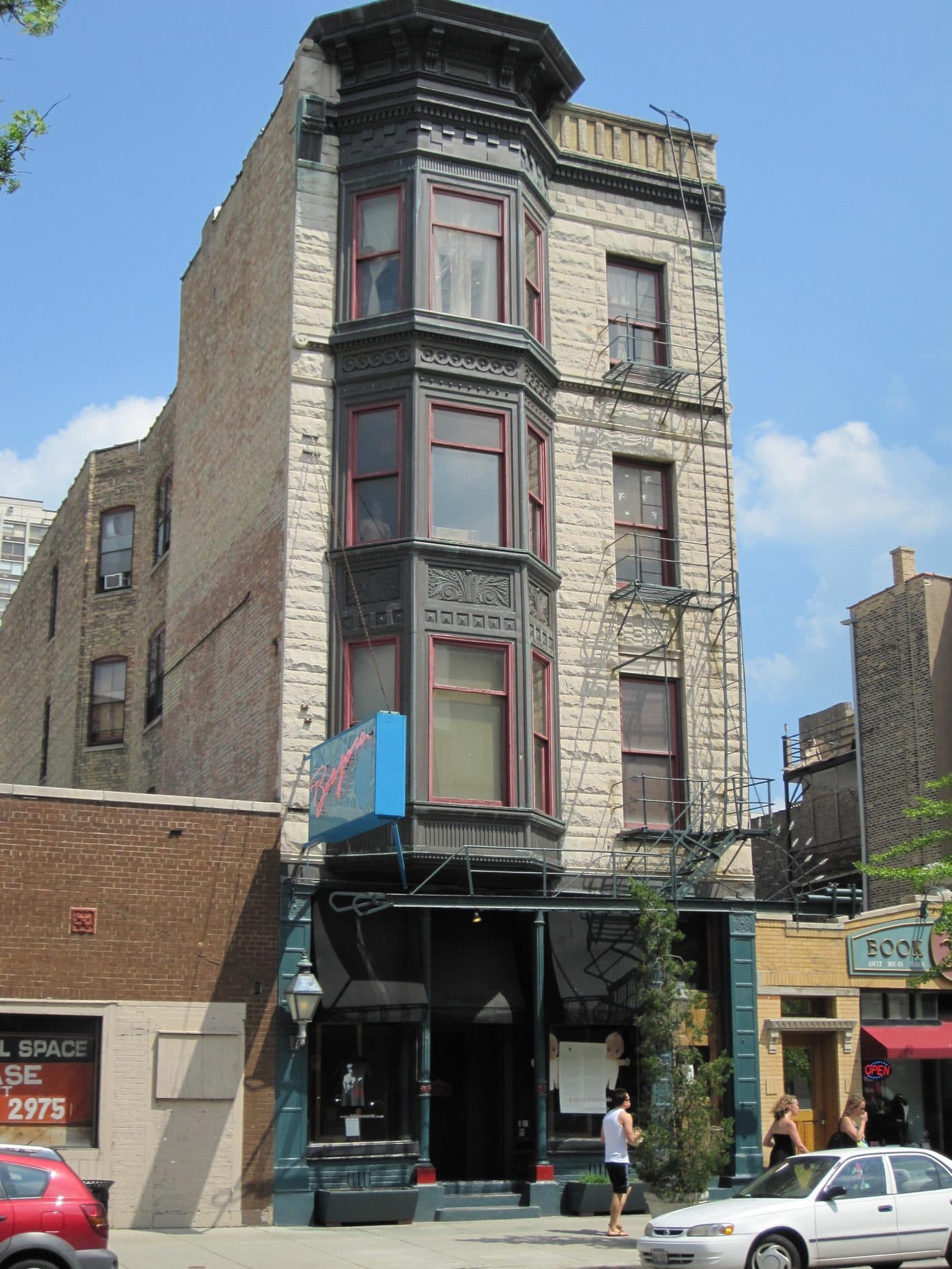 The Bijou Theater at 1349 North Wells Street in Chicago in 2011, a narrow four-storey Victorian greystone with a bay window and a blue neon Bijou sign over the entrance, with an adult movies shop next door.