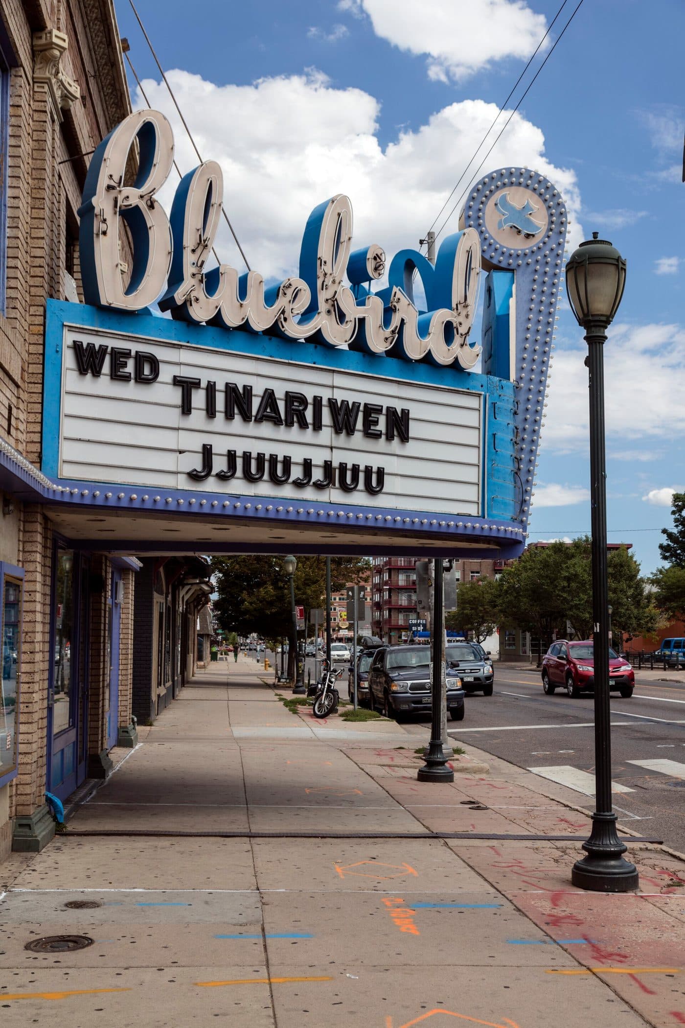 The Bluebird Theater at 3317 East Colfax Avenue in Denver, a restored brick and terracotta facade with a large vertical neon sign reading Bluebird.