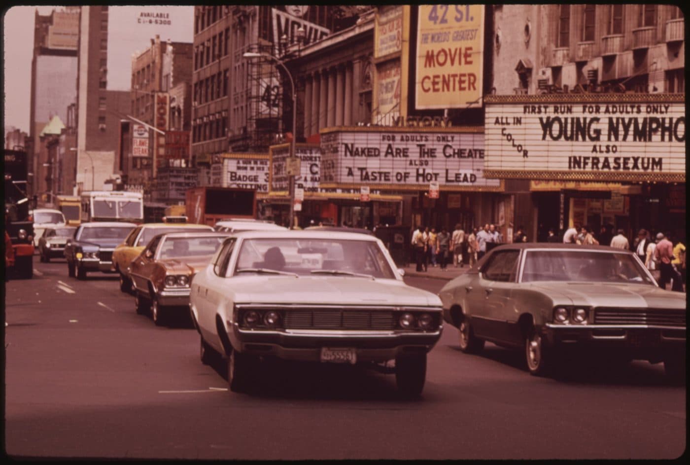 42nd Street just west of Seventh Avenue in August 1973, with cinema marquees reading FOR ADULTS ONLY and a sign advertising 42 St, the world's greatest movie center, above lines of traffic.