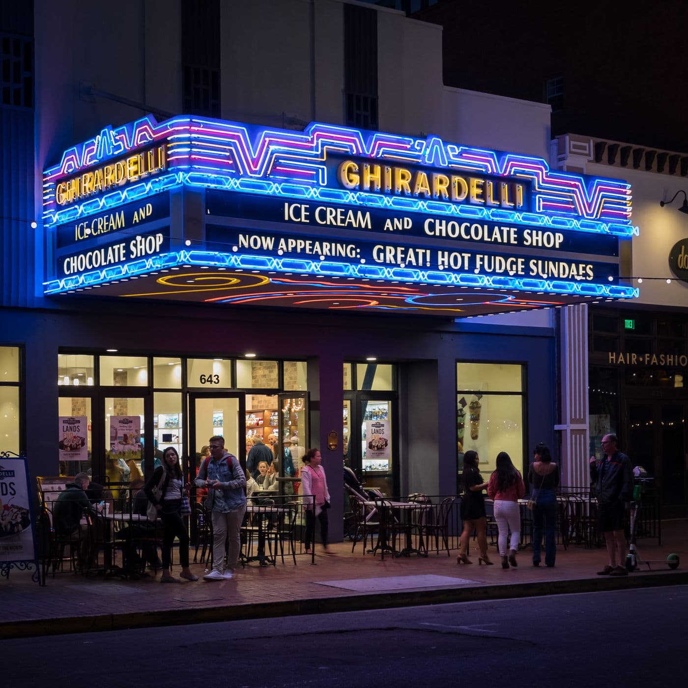 The neon marquee of a former adult cinema in San Diego at night, now reading Ghirardelli Ice Cream and Chocolate Shop.
