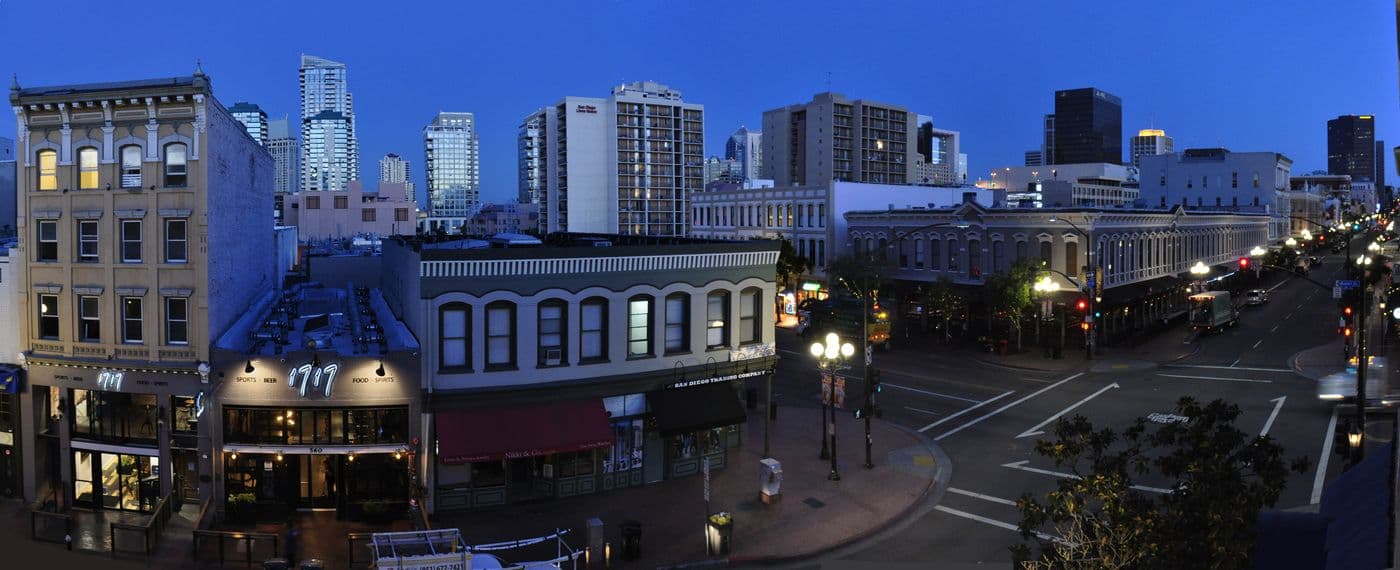 Fifth Avenue at Market Street in San Diego's Gaslamp Quarter, restored brick and stucco storefronts under a clear sky.
